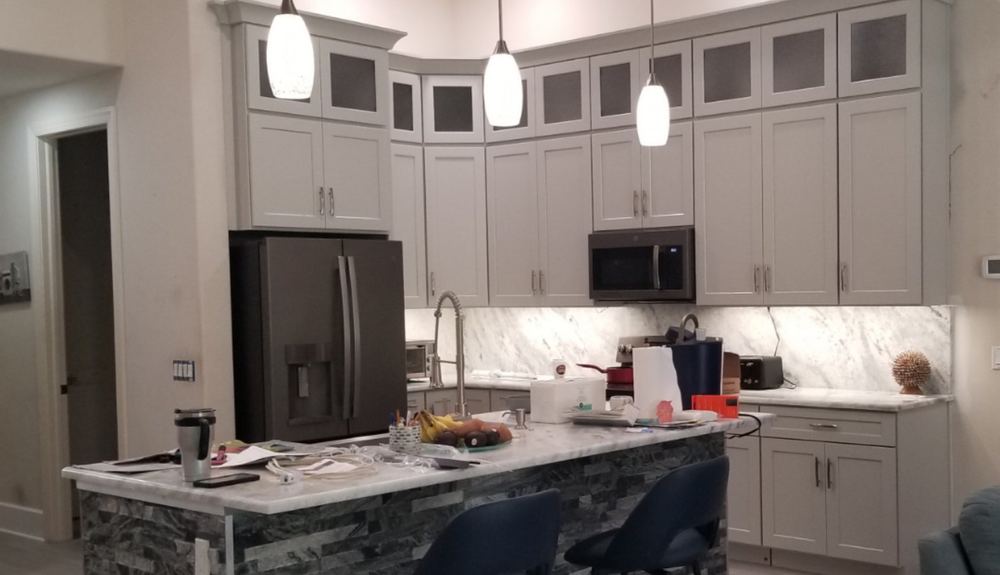 Kitchen after: new white cabinets to the ceiling, marble backsplash and stone island