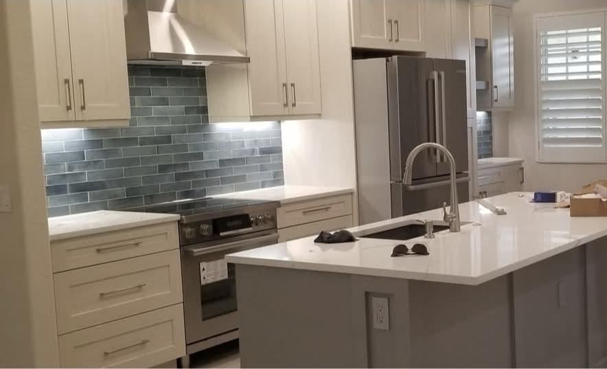 Kitchen after: white shaker cabinets, blue tile backsplash and a new island