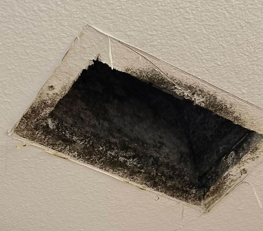 Dark mold growth inside and around a ceiling AC supply vent